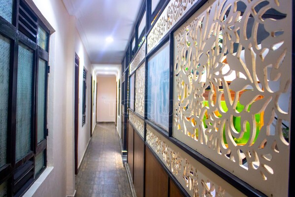 A corridor with patterned decorative screens, a tiled floor, and a view into a room with a door at the end. - Toque Hotel (Nairobi)