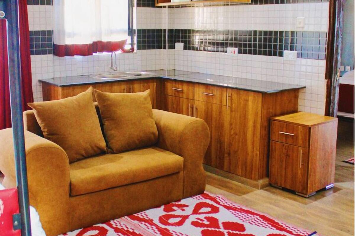 A compact kitchen with a wooden cabinet, a small countertop, and a window with curtains.