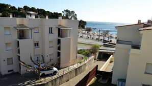 Un edificio residencial con vista al mar, una zona de estacionamiento y un pequeño jardín.