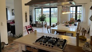 Een keuken met een gasfornuis, een eettafel, stoelen en een groot raam.