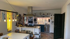 Een kleine keuken met een eethoek, met een fornuis, oven en spoelbak.