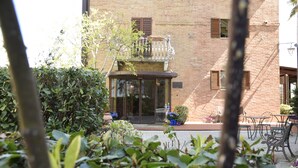A brick building with a balcony, outdoor seating, and potted plants. - Hotel Arcobaleno Siena (Siena)