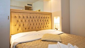 A neatly made bed with a tufted headboard, a bedside lamp, and a mirror above the bed. - Hotel Arcobaleno Siena (Siena)