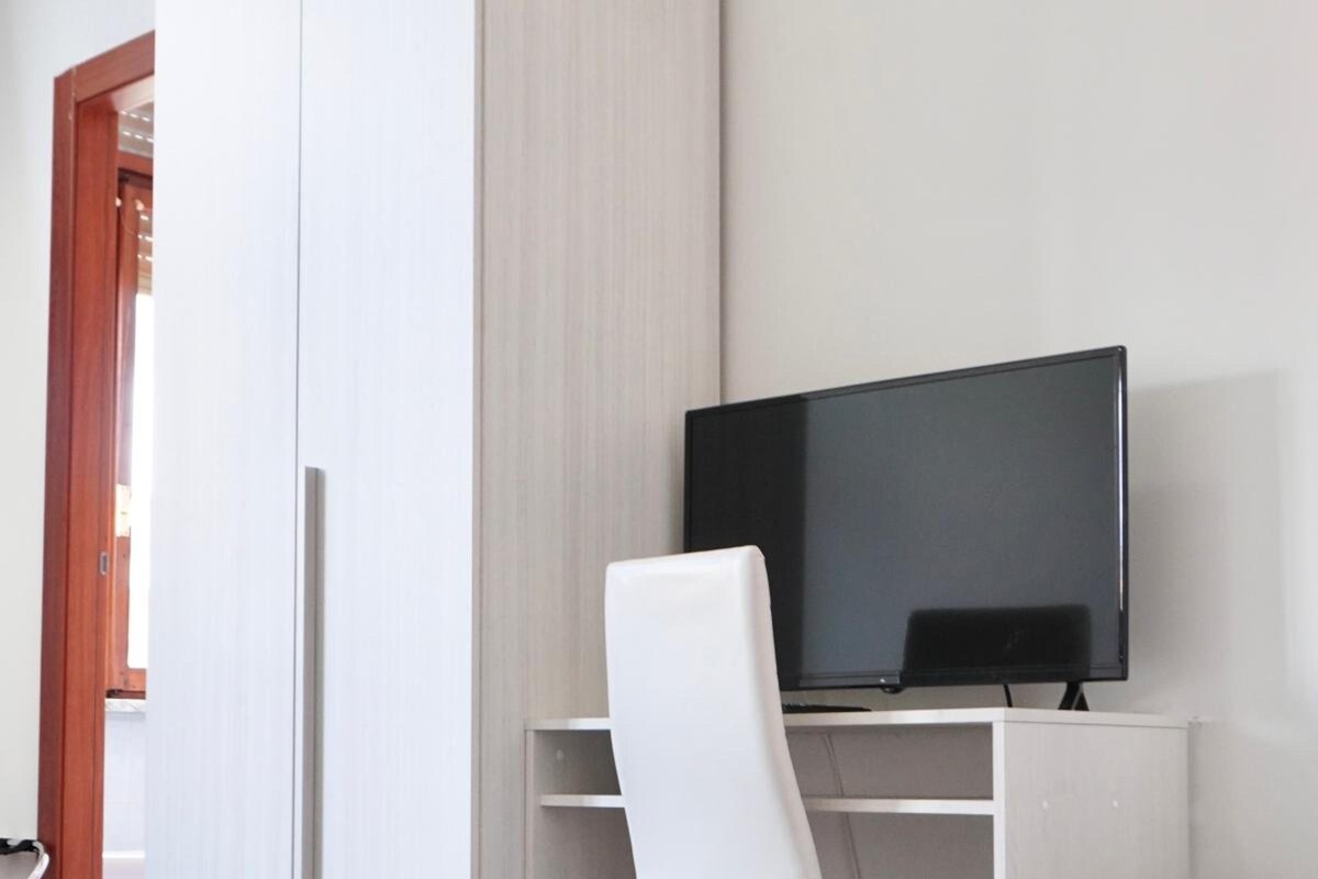 A hotel room with a bed, a desk with a television, and a wardrobe.