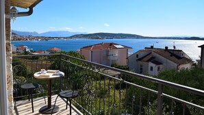 A balcony with a table and chairs overlooking a coastal town and sea. - Villa Julio's  fully separate stone house , located in the middle of garden (Seget Donji)
