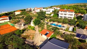 A residential area with multiple white buildings, a swimming pool, and a hillside in the background. - Villa Julio's  fully separate stone house , located in the middle of garden (Seget Donji)