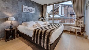 Un dormitorio moderno con una cama grande, vistas de edificios a través de una ventana y una pared de piedra.