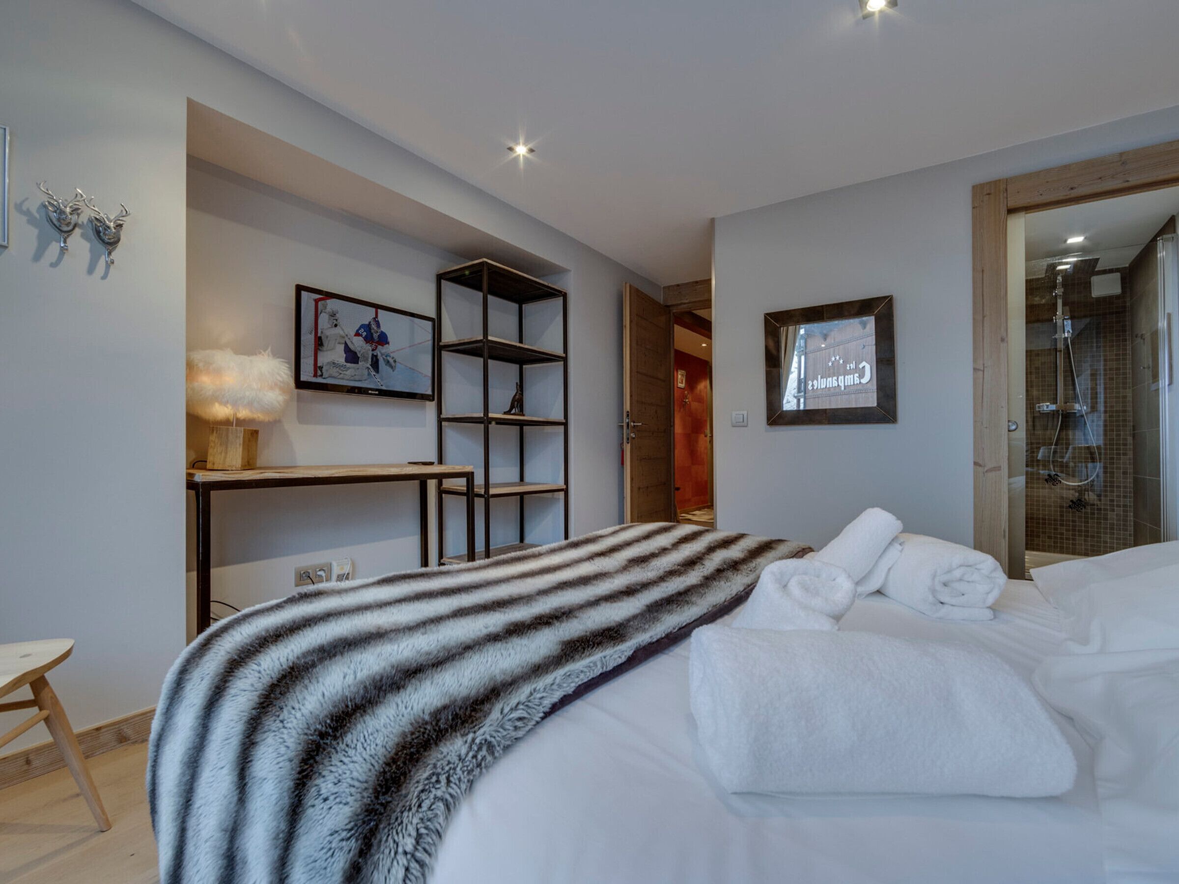 Een moderne hotelkamer met een bed, een bureau, een televisie en een douche.