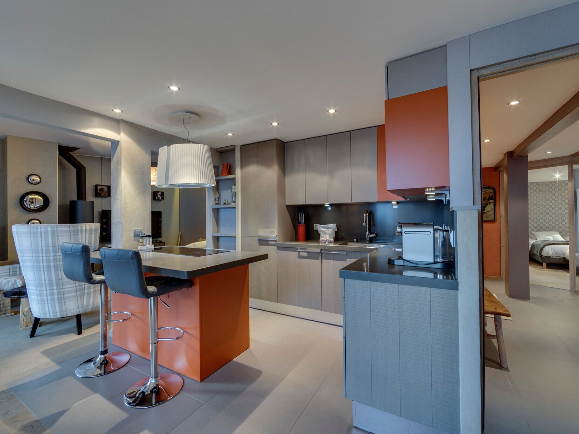 Una cucina moderna con isola centrale, sgabelli da bar e zona pranzo con tavolo e sedie.