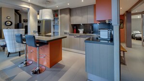 Una cocina moderna con una isla central, taburetes de bar y un comedor con mesa y sillas.