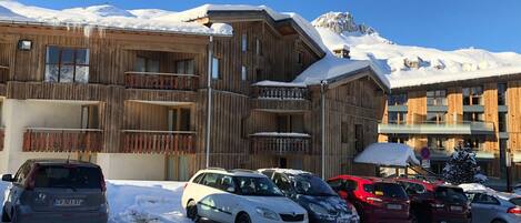 A wooden building with balconies and a parking lot with cars.