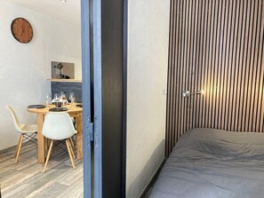 Een moderne kamer met een bed, een eethoek met een tafel en stoelen, en een keukenhoek.