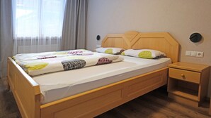 Ein Einzelbett mit Holz-Kopfteil, einem Nachttisch und einem Beistelltisch.
