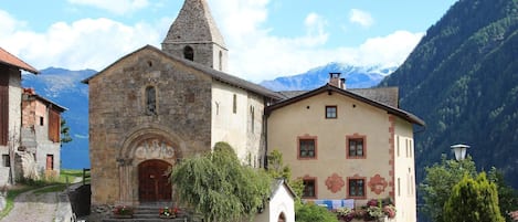 A church with a stone bell tower and a traditional building with a gabled roof.