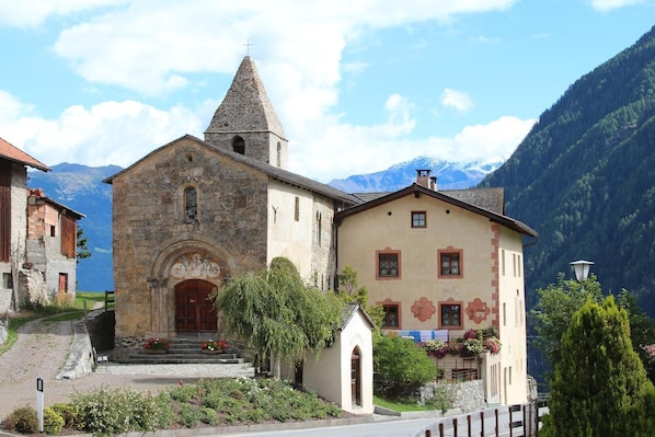 A church with a stone bell tower and a traditional building with a gabled roof.