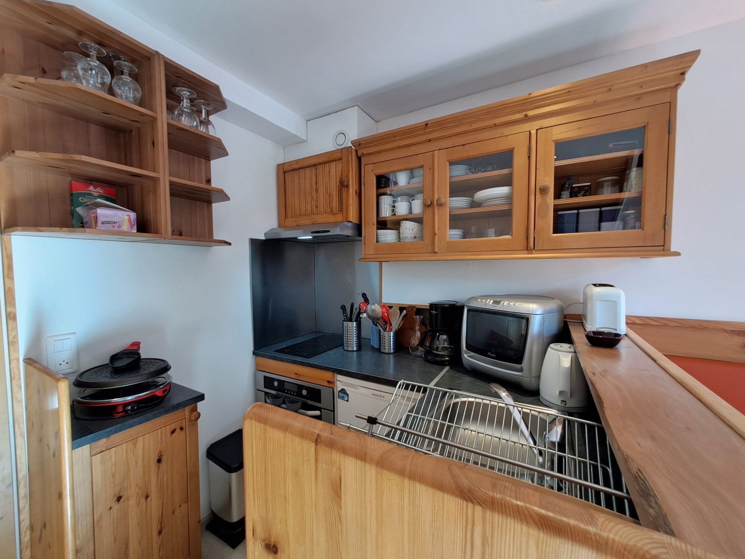 A compact kitchen with wooden cabinets, a built-in oven, a microwave, and a dishwasher.