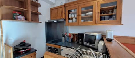A compact kitchen with wooden cabinets, a built-in oven, a microwave, and a dishwasher.