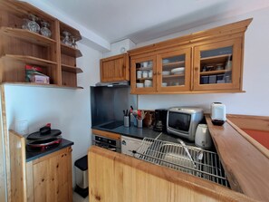 A compact kitchen with wooden cabinets, a built-in oven, a microwave, and a dishwasher.