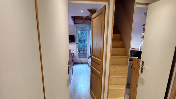 Un couloir avec des portes en bois et un escalier menant à un étage supérieur.