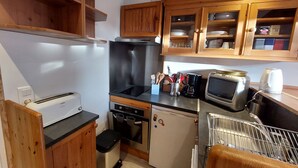 Une cuisine compacte avec des meubles en bois, un grille-pain, une cuisinière, un four à micro-ondes et un petit réfrigérateur.