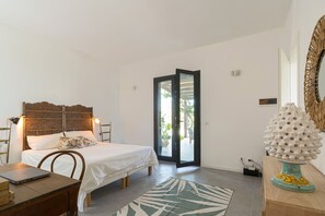 A bedroom with a bed, a desk, a laptop, a decorative vase, and a view of the outdoors through a sliding door. - Nice villa with pool near Noto, Sicily (Noto)