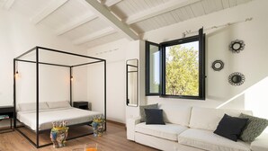 A modern bedroom with a four-poster bed, a sofa, and a dining table with orange juice. - Nice villa with pool near Noto, Sicily (Noto)