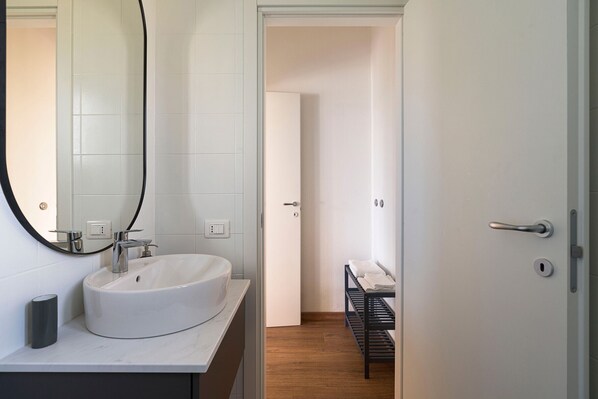 A modern bathroom with a white sink, a large mirror, and a wooden floor. - Nice villa with pool near Noto, Sicily (Noto)