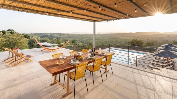 A covered outdoor dining area with a view of the countryside, a pool, and a hammock. - Nice villa with pool near Noto, Sicily (Noto)