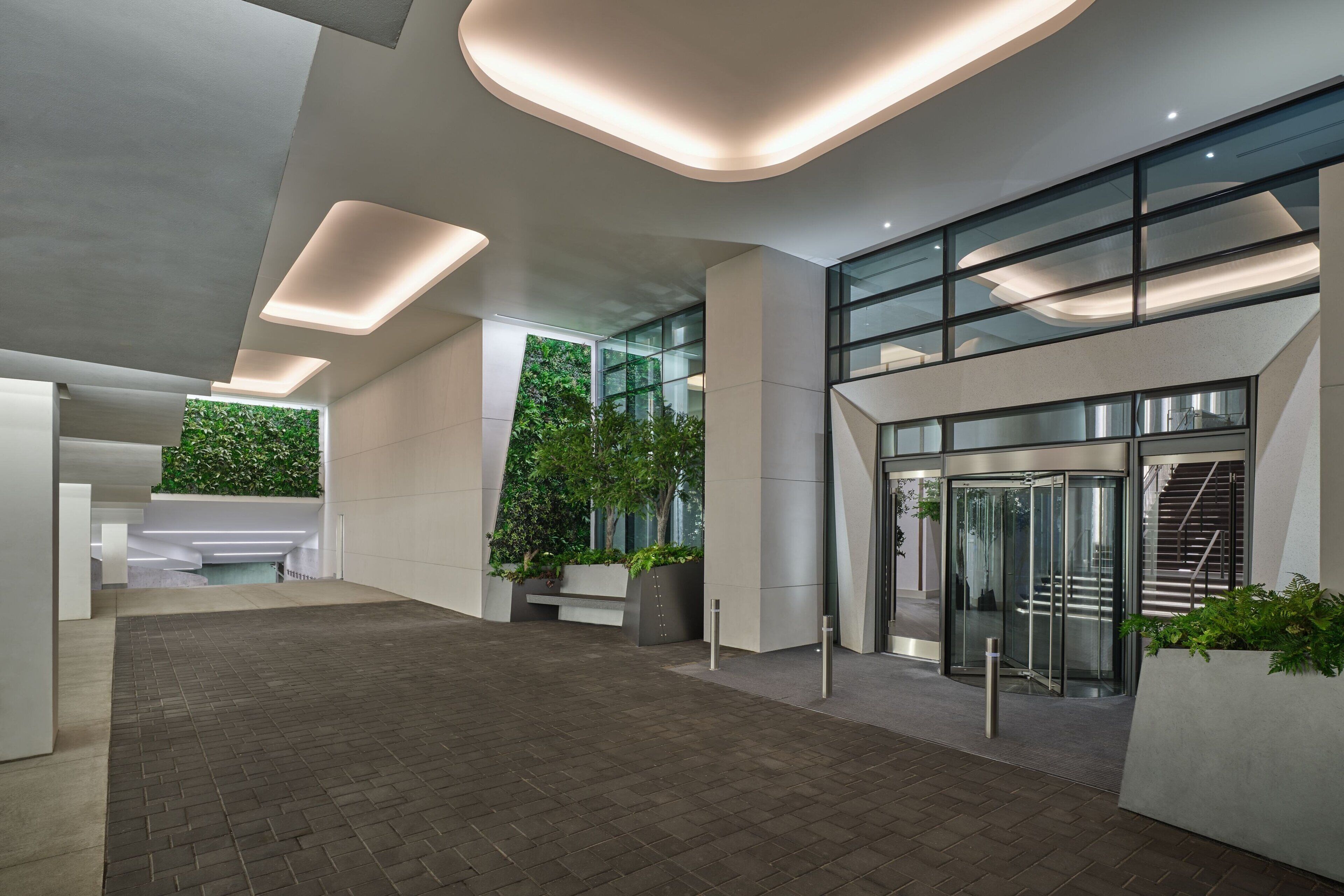 Um lobby moderno com entrada de vidro, área de estar e escadaria.