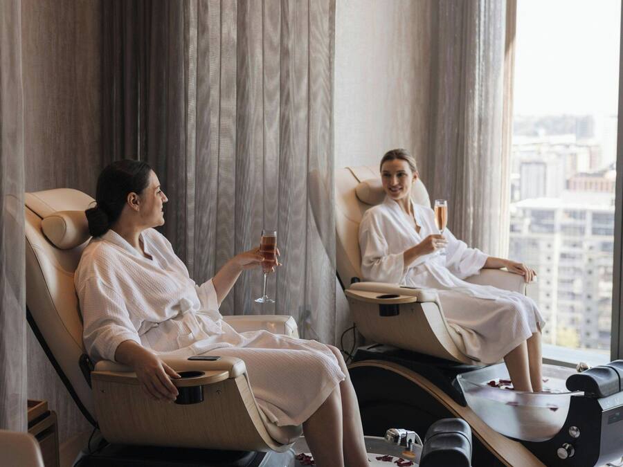 Two massage chairs in a room with large windows and curtains.