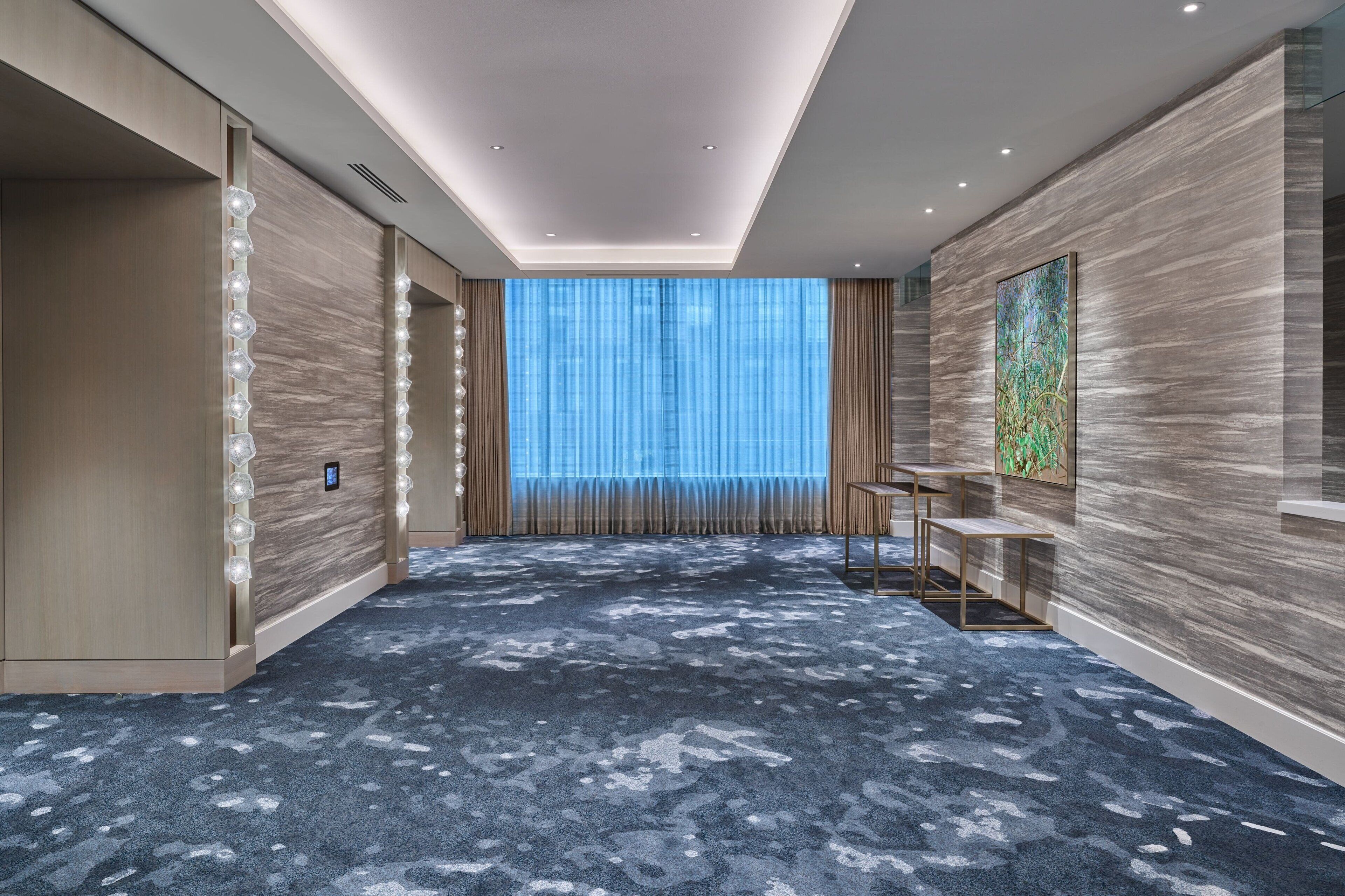 A modern hotel room with a large window, a blue carpet, and a wooden wall.