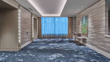 A modern hotel room with a large window, a blue carpet, and a wooden wall.
