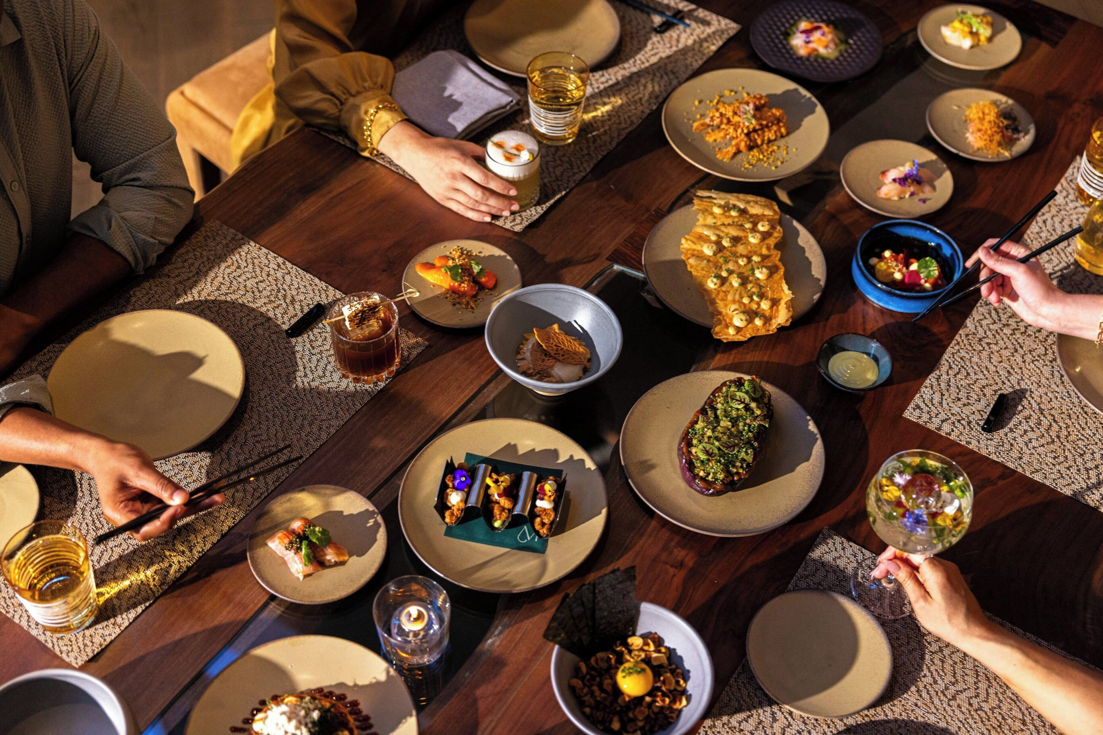 A dining table with various dishes, glasses, and chopsticks.