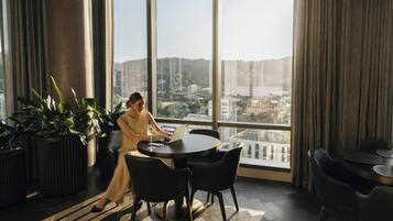 A modern hotel room with a large window, a round table, and several chairs.