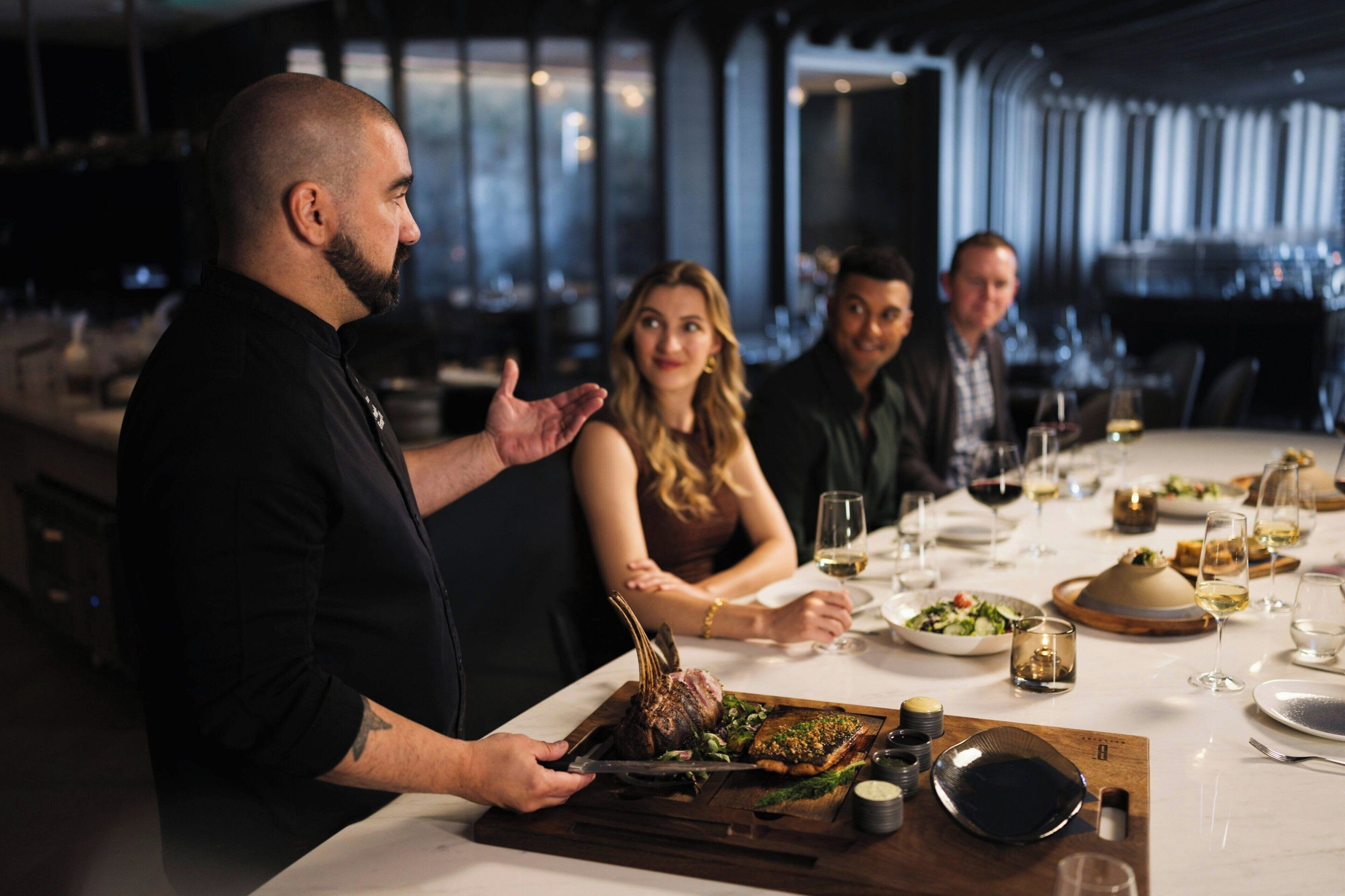 Ein Restaurantambiente mit einem Tisch für vier Personen, der mit einem Gericht mit Knochen, Weingläsern und einem Dessertteller gedeckt ist.