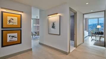 A modern hotel corridor with framed artwork on the walls, a dining area with a view, and a spacious room with a large window.