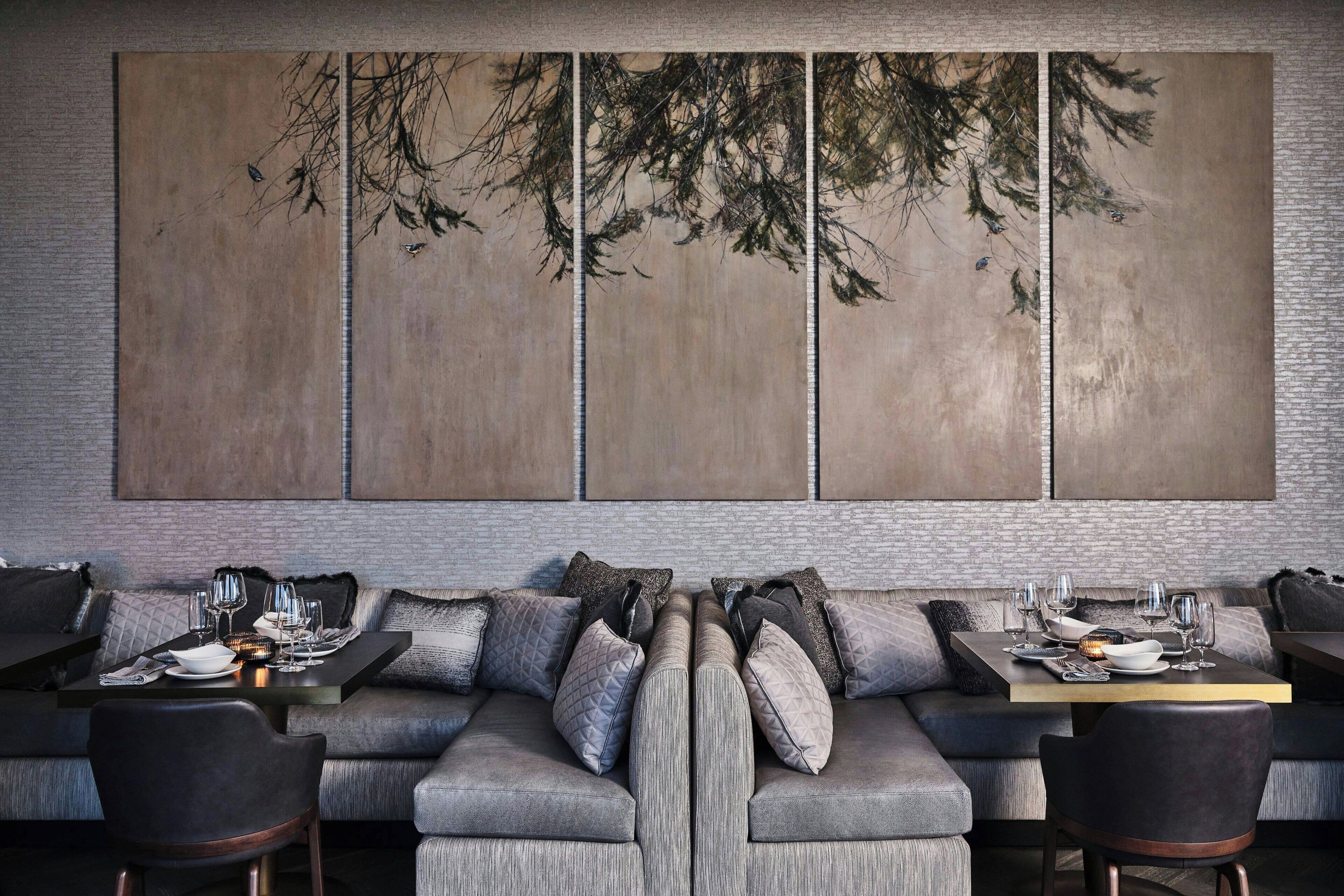 A modern dining area with a sofa and a dining table set for two, featuring a large abstract painting on the wall.