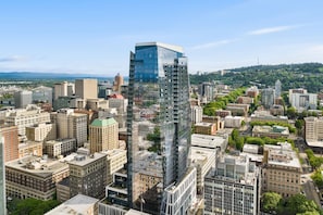 A high-rise building with a glass facade, surrounded by other buildings and greenery.