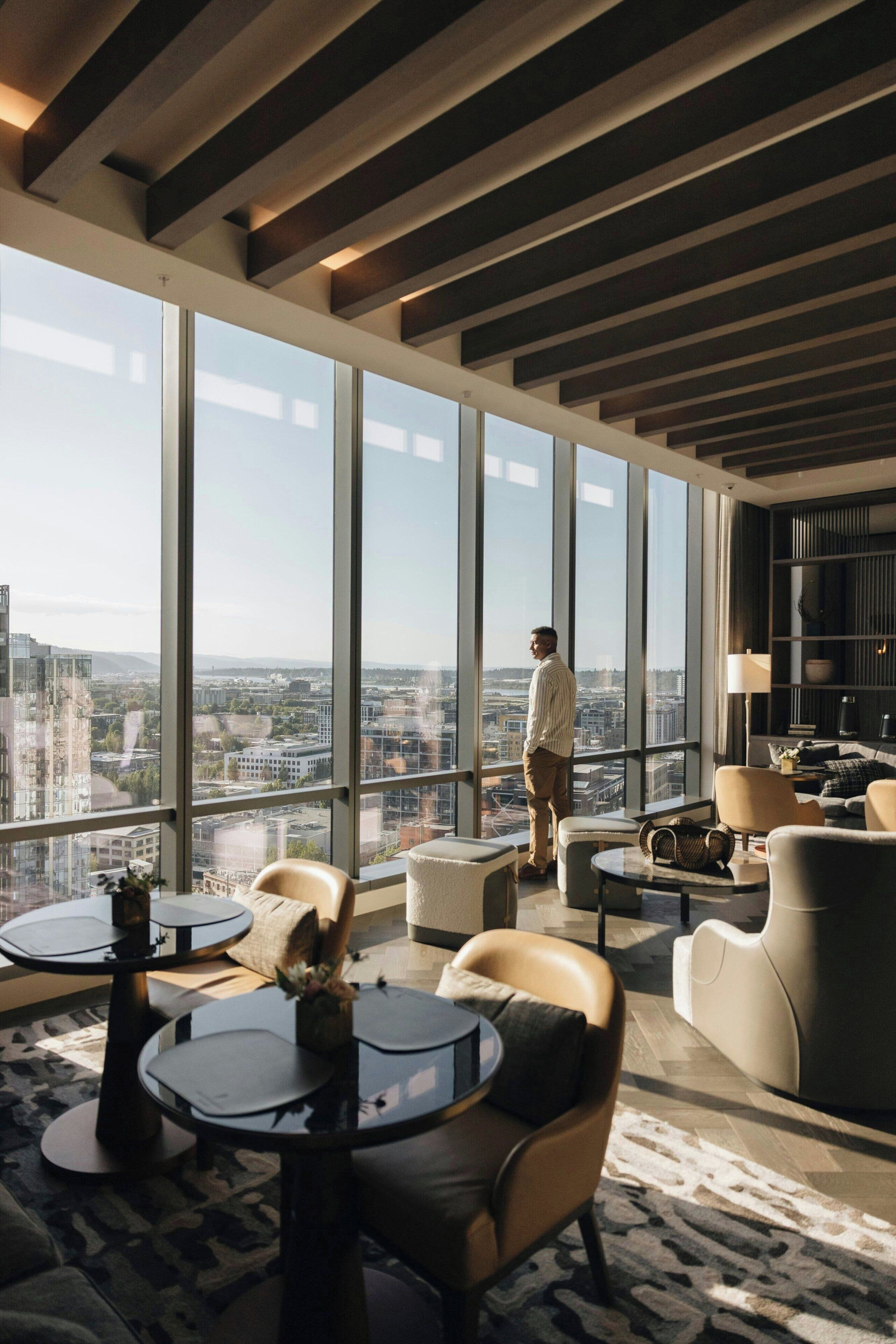 A modern lounge with large windows, a city view, and contemporary furniture.