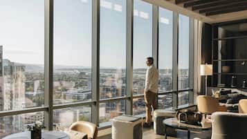 A modern lounge with large windows, a city view, and contemporary furniture.