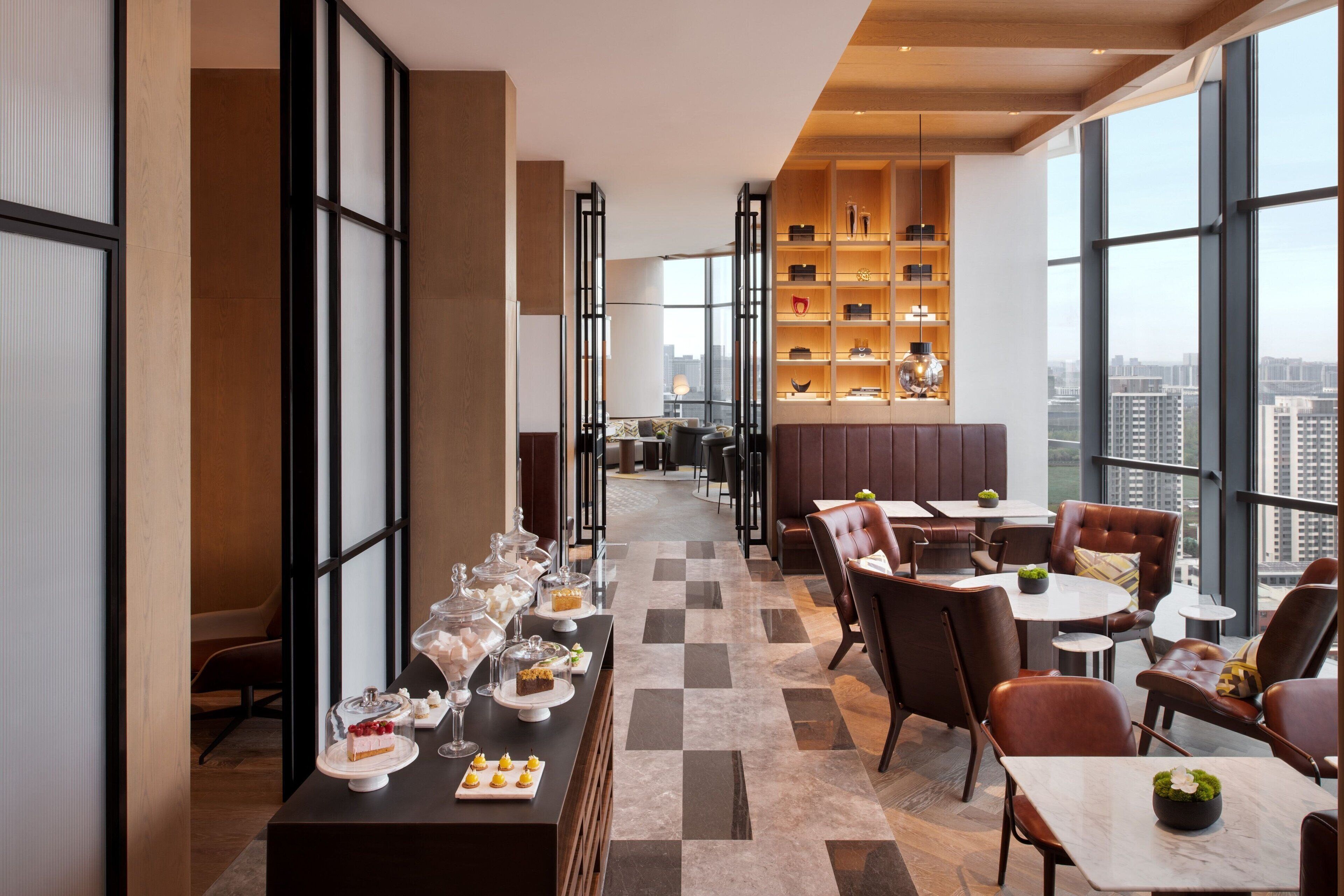 A modern restaurant with a long counter, leather seating, and a city view.