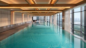 A modern indoor swimming pool with a long, narrow design, large windows, and a view of the cityscape. - Sheraton Xi'An Chanba (Xi'an)