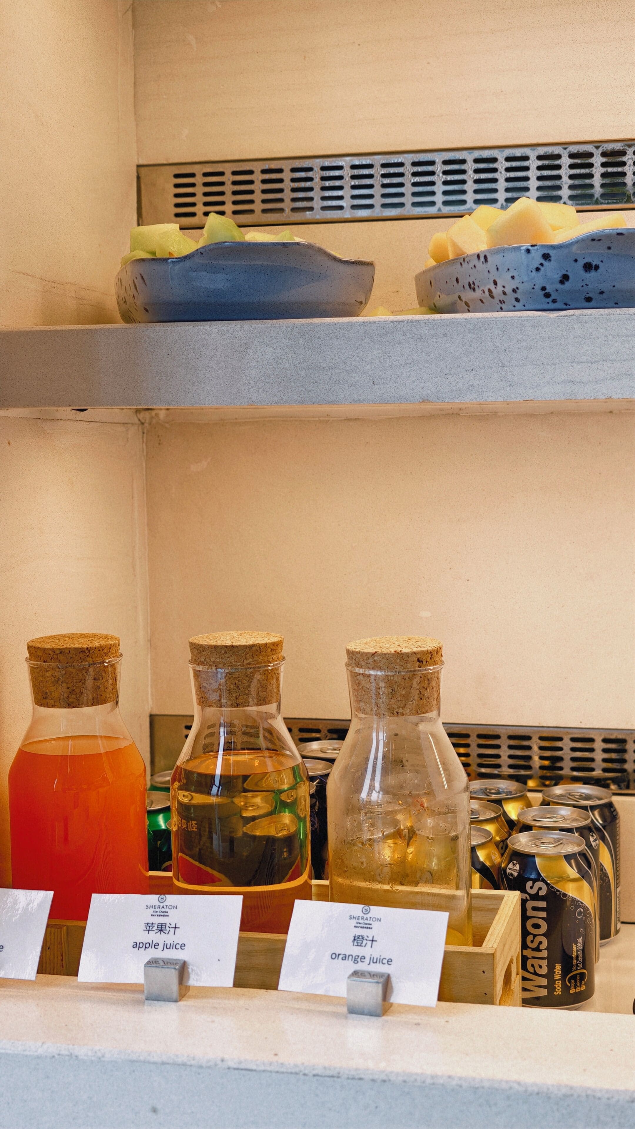 A shelf with various juice bottles and a container of soda water.
