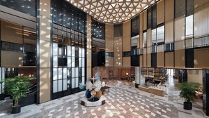 A spacious lobby with a geometric patterned floor, large windows, and a central seating area with a decorative sculpture. - Sheraton Xi'An Chanba (Xi'an)