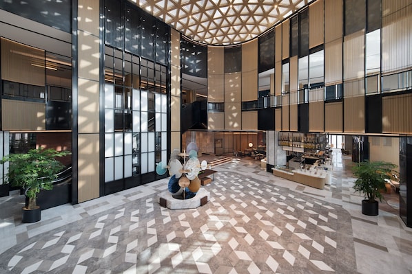 A spacious lobby with a geometric patterned floor, large windows, and a central seating area with a decorative sculpture. - Sheraton Xi'An Chanba (Xi'an)