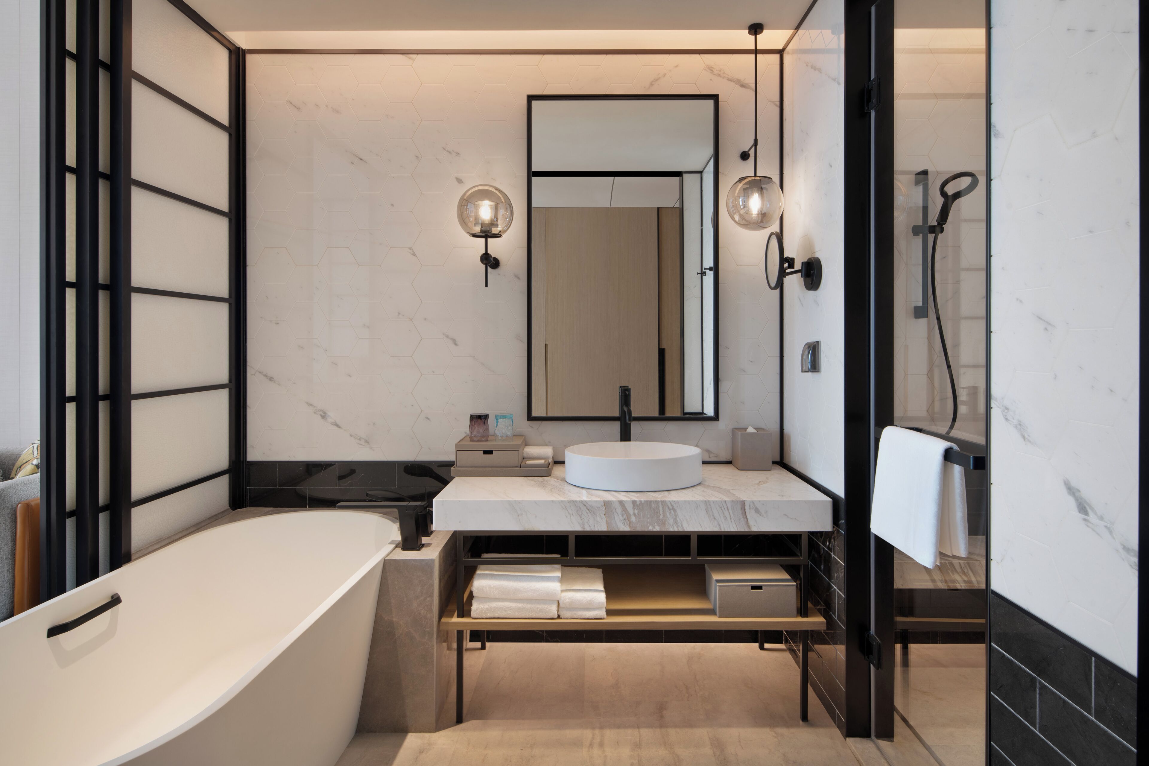A modern bathroom with a freestanding bathtub, a round sink, and a large mirror.