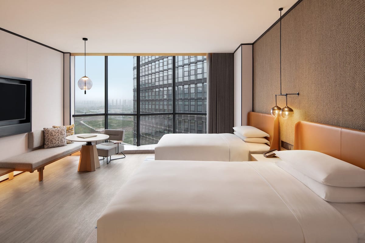 Ein modernes Hotelzimmer mit einem großen Bett, einer Sitzecke, einem kleinen Tisch und einem Fernseher.