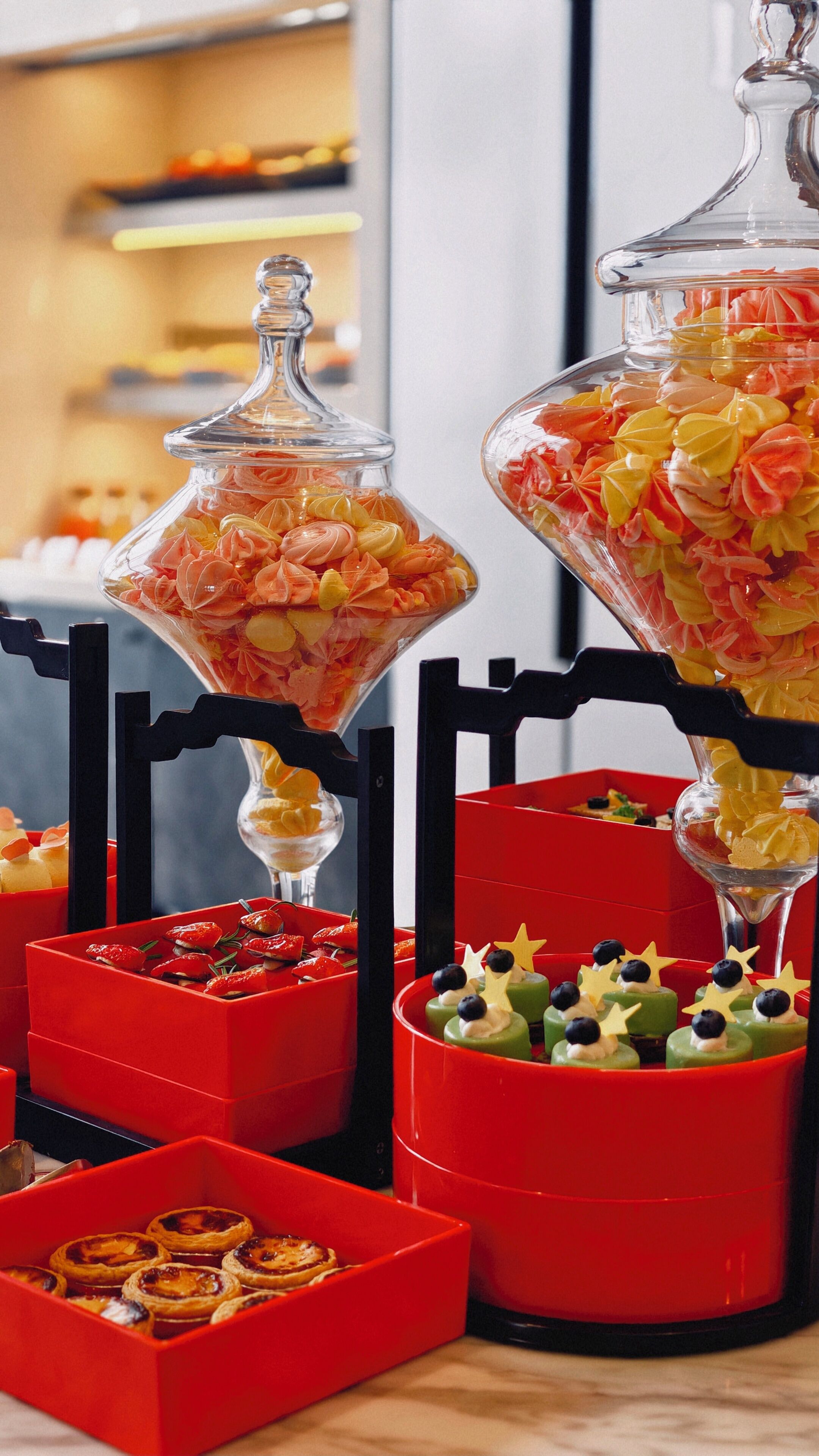 A variety of food items displayed in clear containers and red boxes, including pastries and desserts.