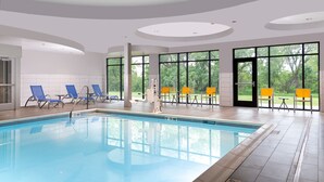 A swimming pool with blue and yellow lounge chairs, large windows, and a modern ceiling design. - Fairfield Inn & Suites By Marriott Norfolk (Norfolk)