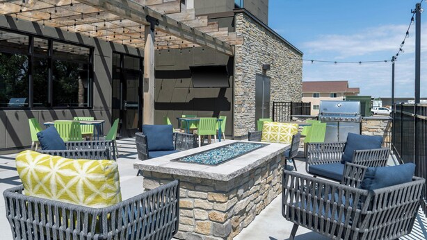 An outdoor seating area with wicker chairs and a stone fire feature. - Fairfield Inn & Suites By Marriott Norfolk (Norfolk)